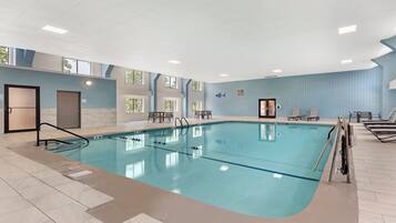 Piscina interior con carriles delimitados, vestuario y zona de estar con sillones.