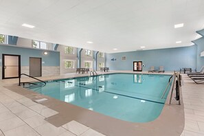 Piscina interior con carriles delimitados, vestuario y zona de estar con sillones.