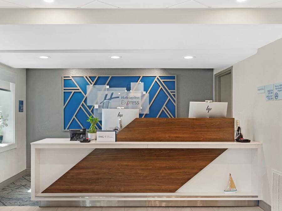 Uma receção de hotel com design moderno, incluindo um painel de parede geométrico azul e um detalhe em madeira.