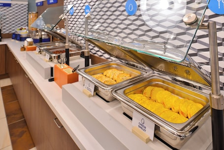 A buffet with various food items and a patterned wall in the background.