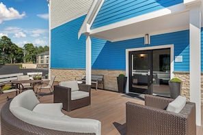 A covered outdoor patio with wicker furniture, a stone wall, and a view of the surrounding area.