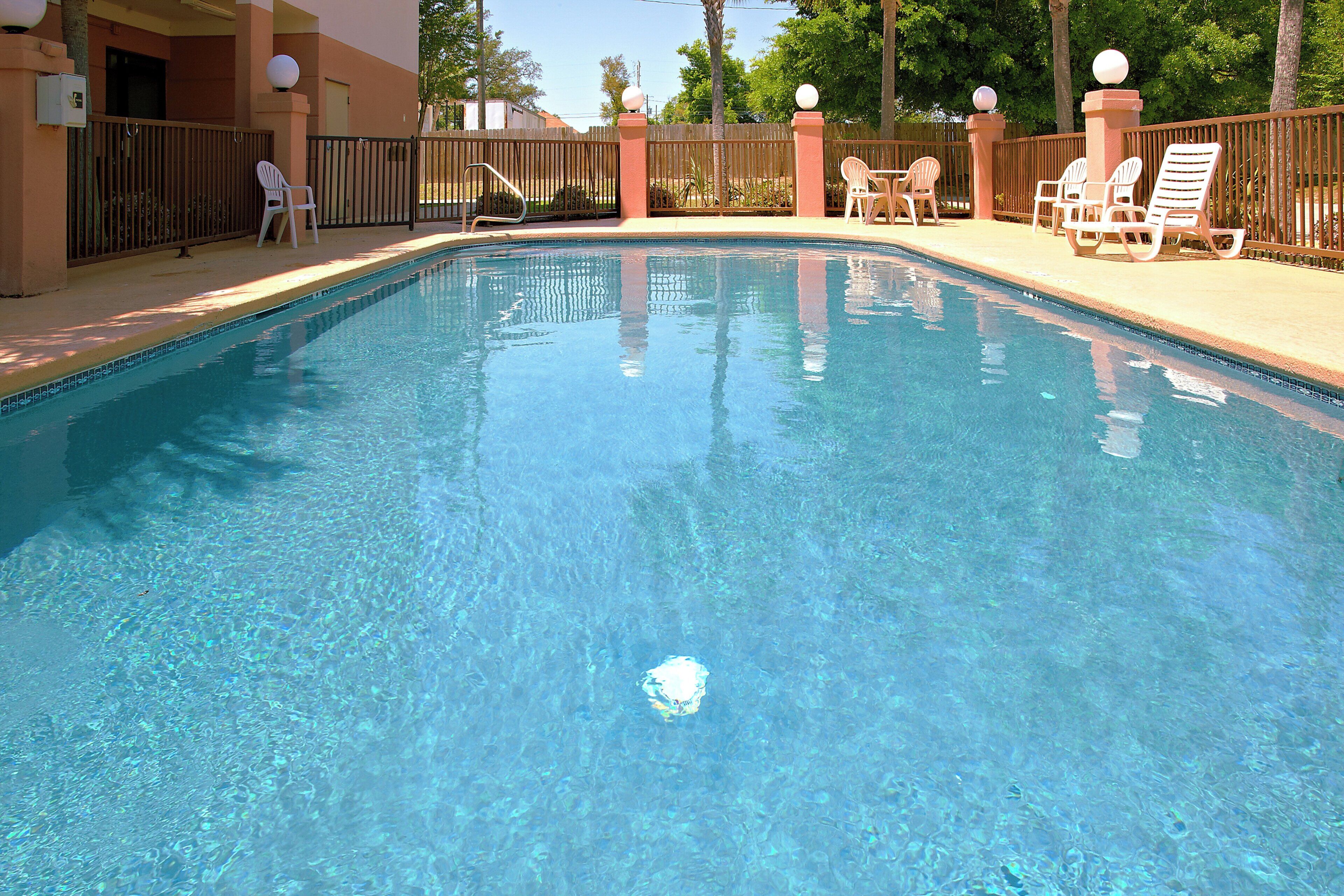 Une piscine aux eaux cristallines, entourée d’une terrasse en bois et de chaises longues.