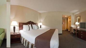 A hotel room with a large bed, two bedside tables with lamps, a television, and a desk with a chair.