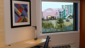 A room with a desk, chair, air conditioner, and a window with a view of a building with a sign that reads "Santana." - Holiday Inn Express Biloxi - Beach Blvd by IHG (Biloxi)