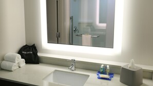 A bathroom with a large mirror, a sink, a towel rack, and a hair dryer bag. - Holiday Inn Express Biloxi - Beach Blvd by IHG (Biloxi)