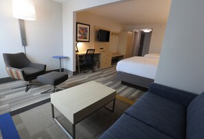 Une chambre d’hôtel comprenant un lit, un bureau, une chaise, une petite table et un canapé.