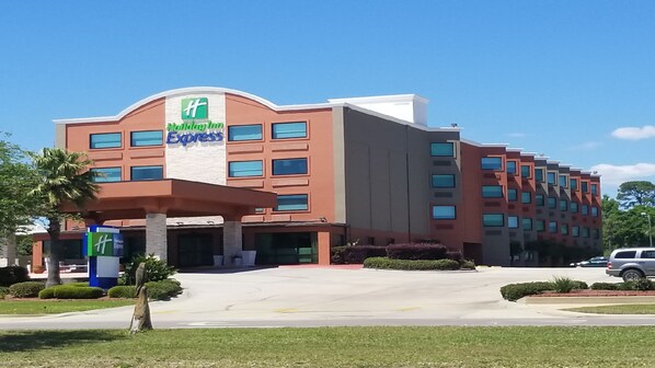 Un hotel Holiday Inn Express con un diseño moderno, que cuenta con una entrada amplia y un estacionamiento.
