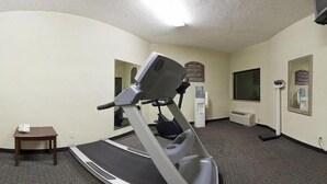 A hotel room with a treadmill, a small table, a water dispenser, and a mirror. - Holiday Inn Express Biloxi - Beach Blvd by IHG (Biloxi)