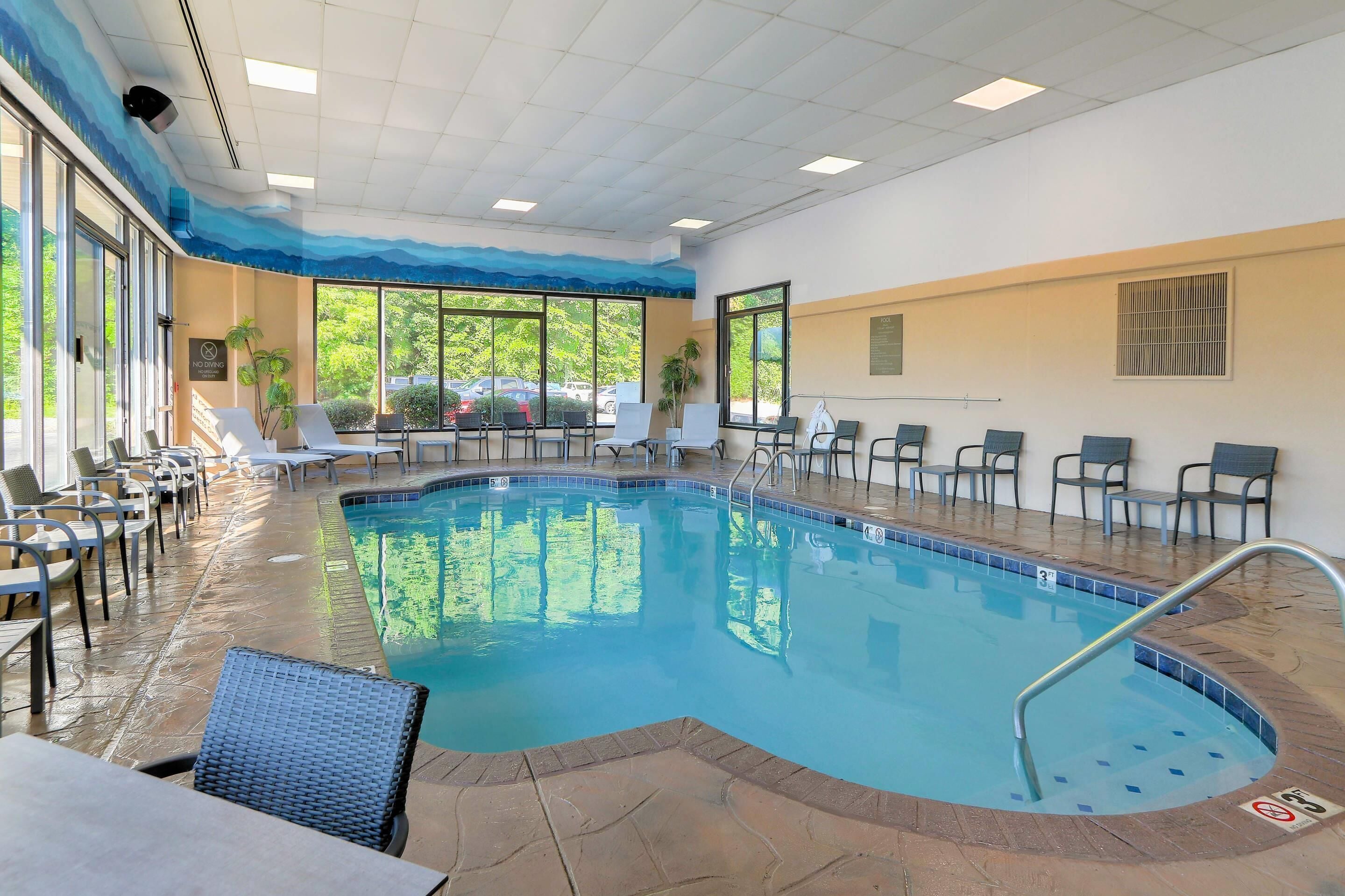 A pool area with lounge chairs and a tiled floor.