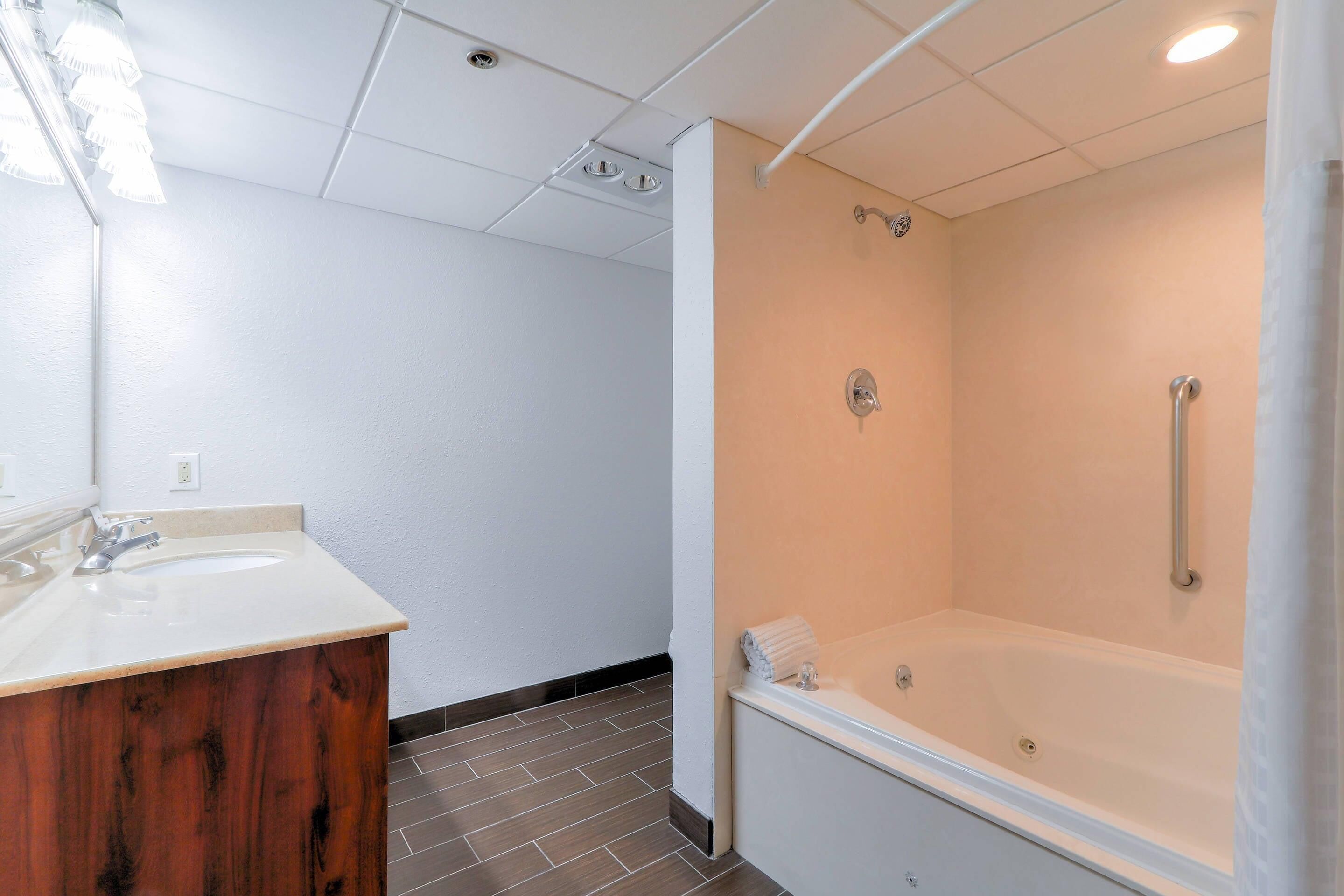 Une salle de bain avec un meuble-lavabo en bois, une baignoire et une douche.