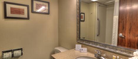 A bathroom with a sink, mirror, framed pictures on the wall, and a toilet.