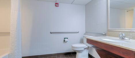 A modern bathroom with a white toilet, a sink with a mirror, and a shower curtain.