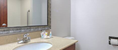 A bathroom with a sink, mirror, and toilet.