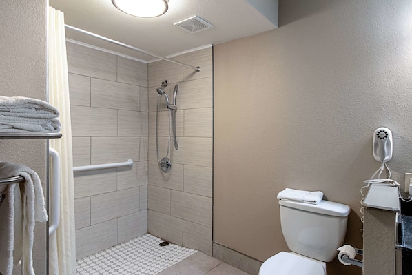 A bathroom with a shower, toilet, and towel rack. - Econo Lodge Kingsville (Kingsville)
