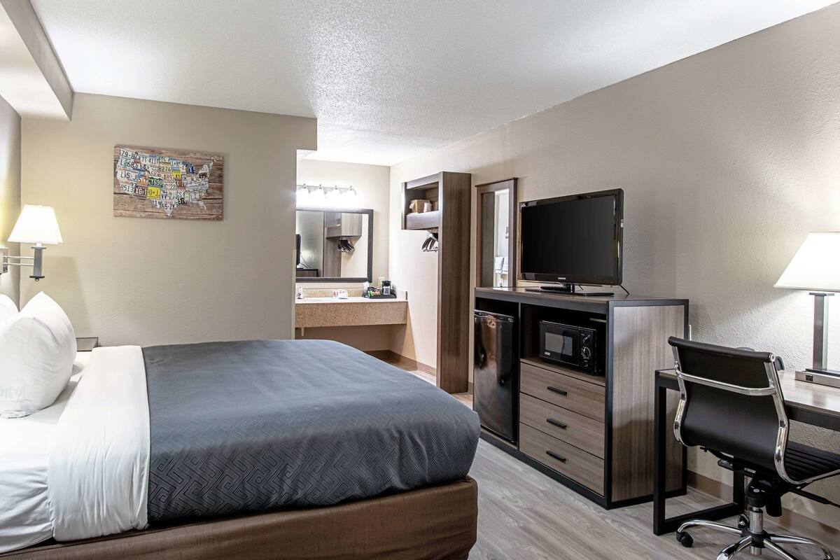 Une chambre d’hôtel équipée d’un lit, d’un bureau, d’une télévision et d’une kitchenette.