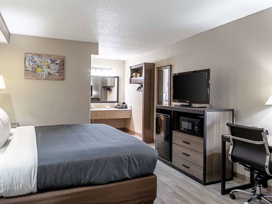 Een hotelkamer met een bed, bureau, televisie en kitchenette.