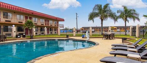 A swimming pool with lounge chairs and a building with a red roof.