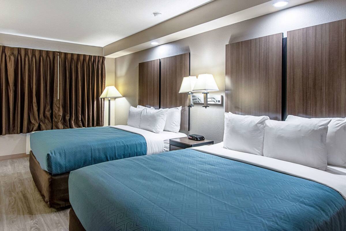 Une chambre d’hôtel avec deux lits, une table de chevet et une lampe.
