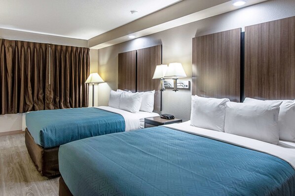 Ein Hotelzimmer mit zwei Betten, einem Nachttisch und einer Lampe.