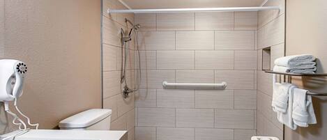 A modern bathroom with a shower, toilet, and a hairdryer on a counter.