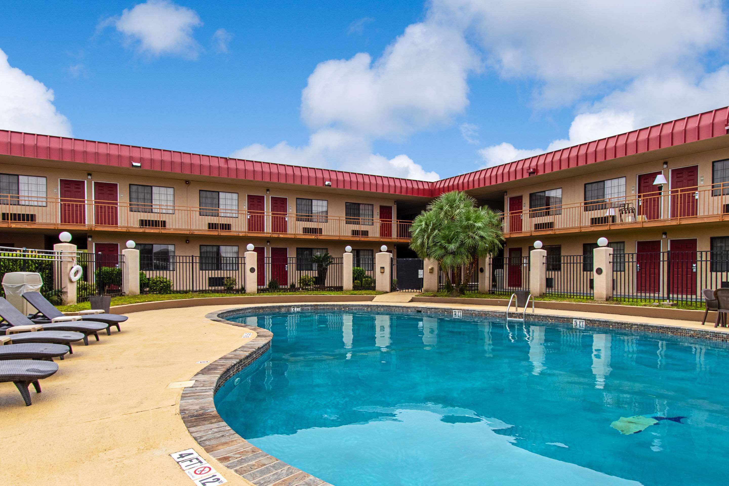Un hotel con piscina, varios balcones y techo rojo.