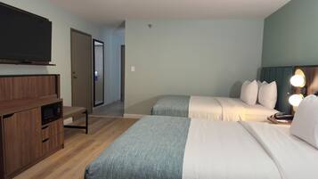 A hotel room with two beds, a TV, a microwave, and a desk.