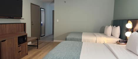 Hotellihuone, jossa on kaksi sänkyä, televisio, mikroaaltouuni ja työpöytä.