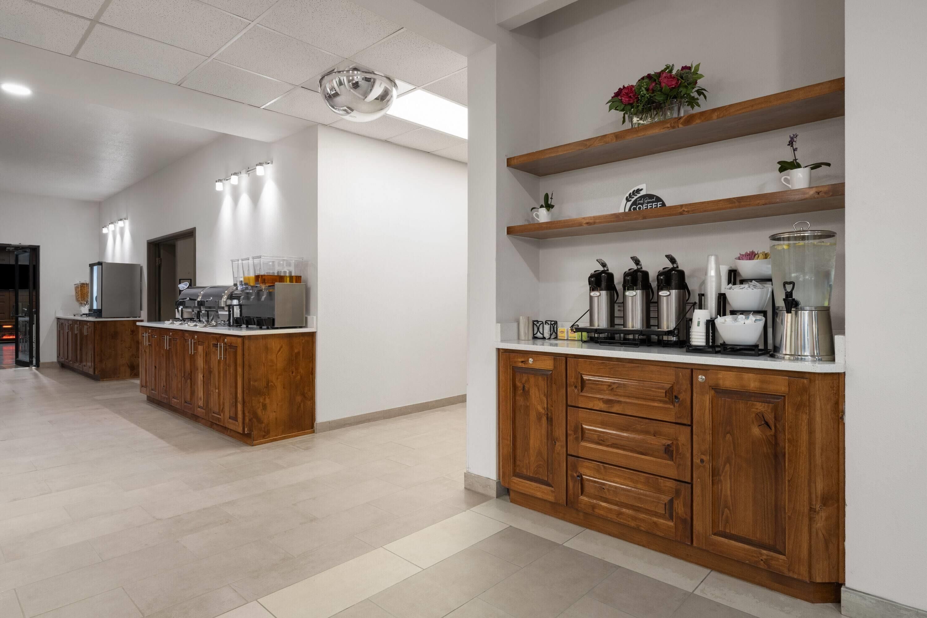 A modern kitchen with wooden cabinets, a central island, and a coffee station.