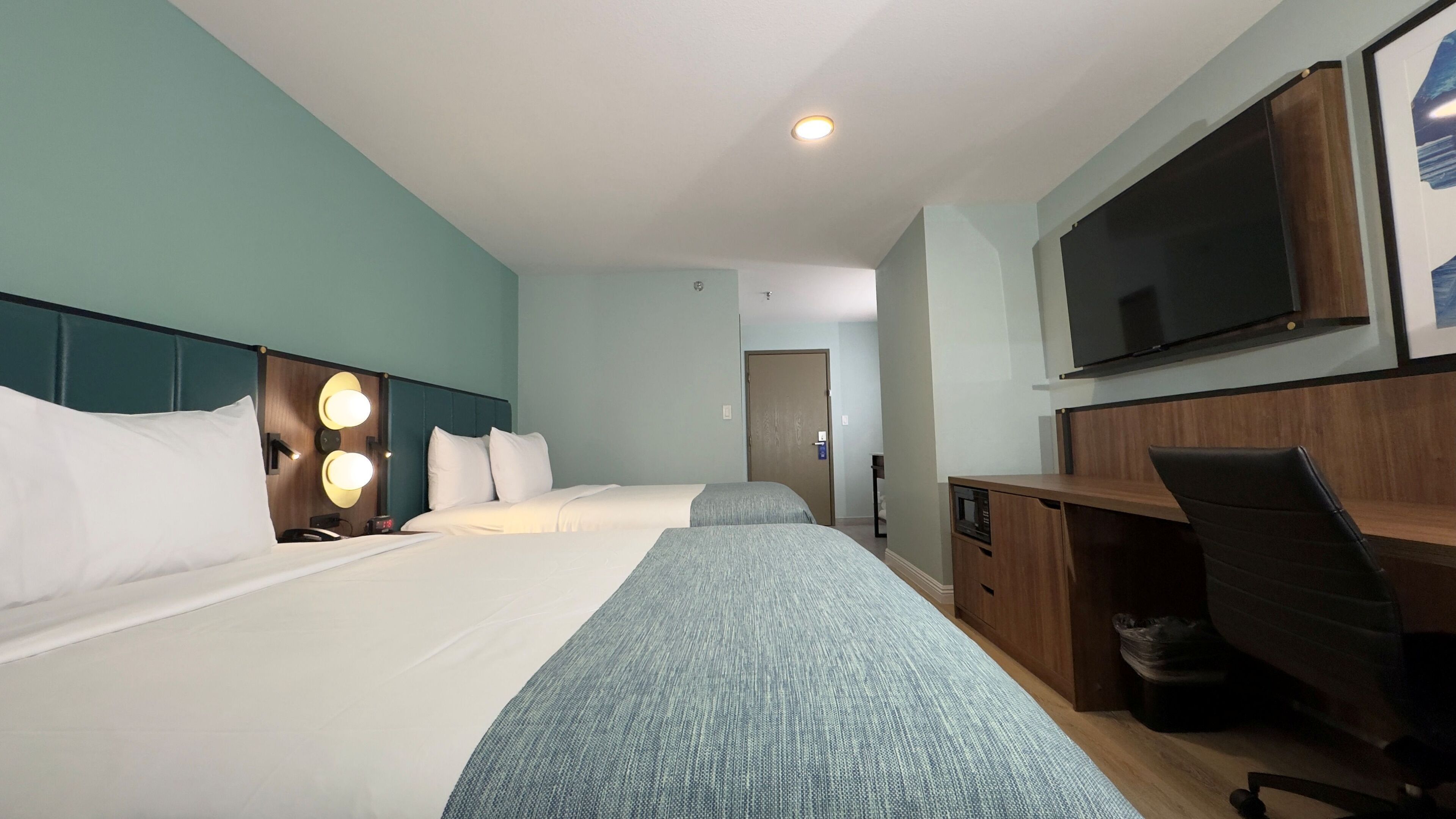 Une chambre d’hôtel avec un grand lit, un bureau, une télévision et une porte.