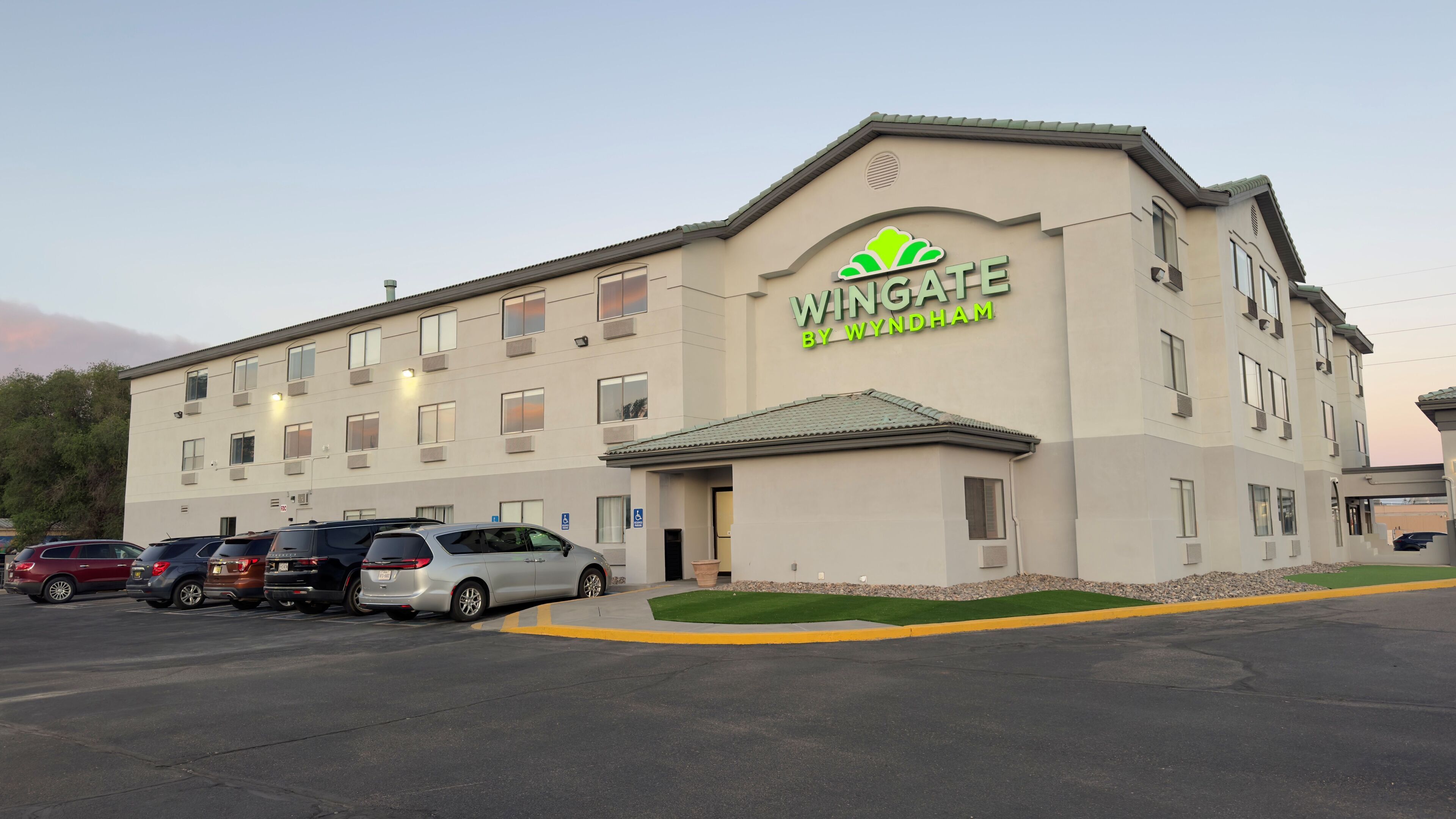 Un hôtel appelé Wingate by Wyndham, doté d’un parking où plusieurs voitures sont garées devant l’entrée.