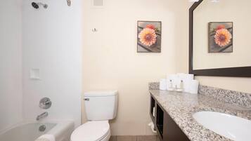 A bathroom with a bathtub, toilet, and sink. There are two framed floral pictures on the wall.