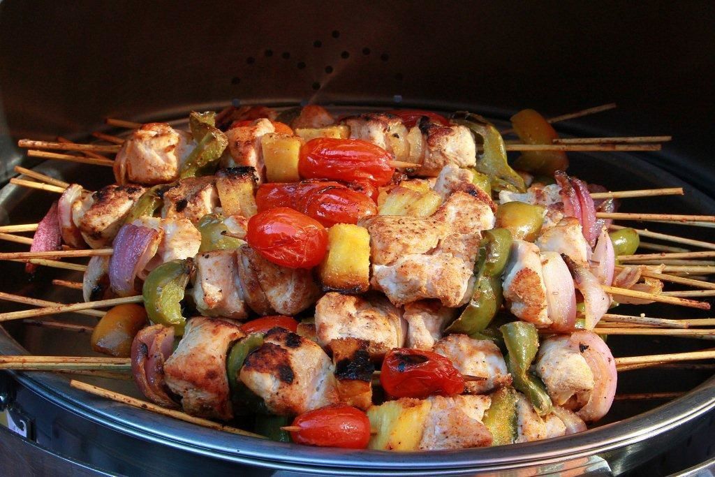 A grill with skewers of chicken, bell peppers, and onions.