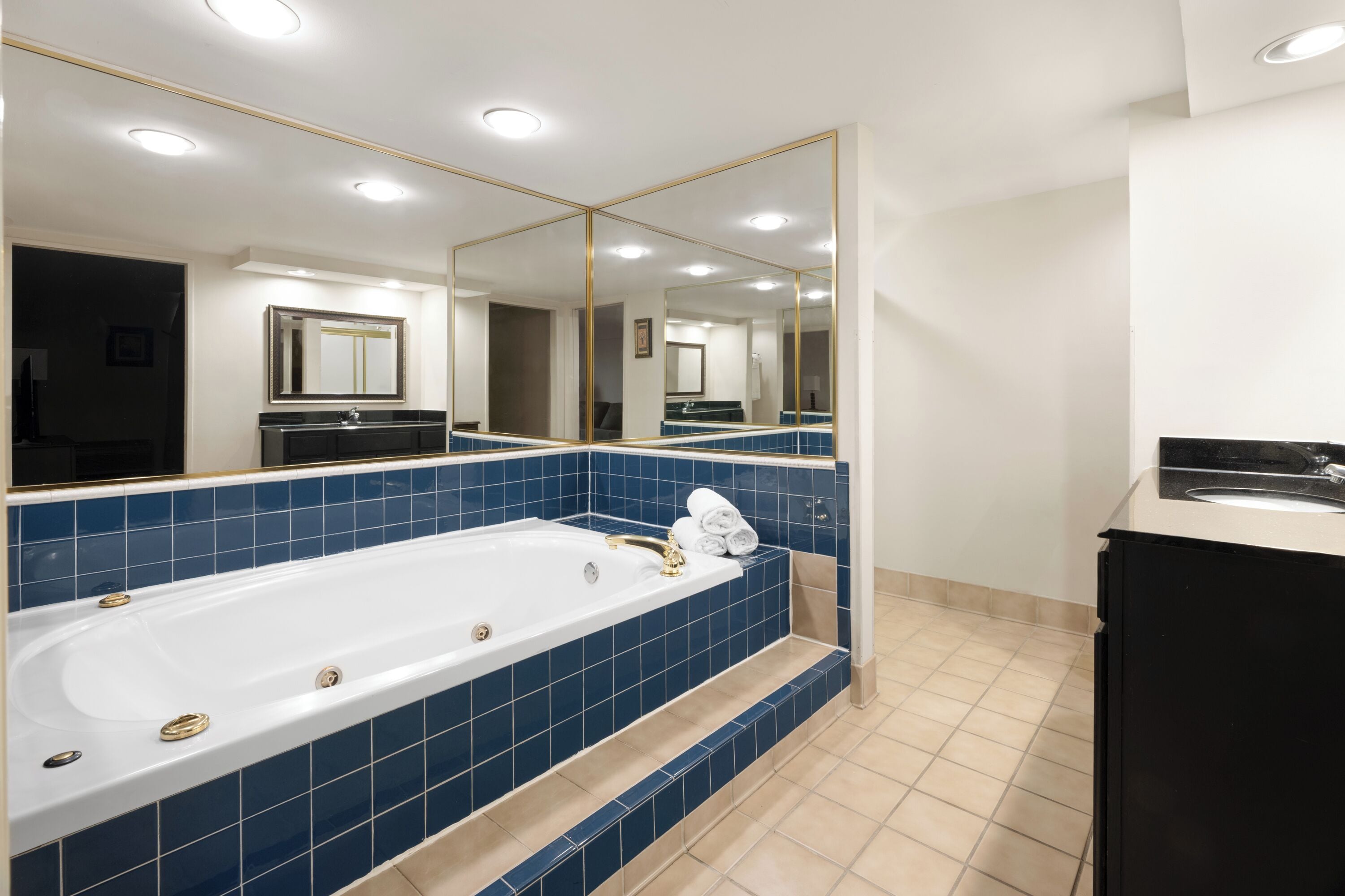 A modern bathroom with a large bathtub, a mirror, and a sink.