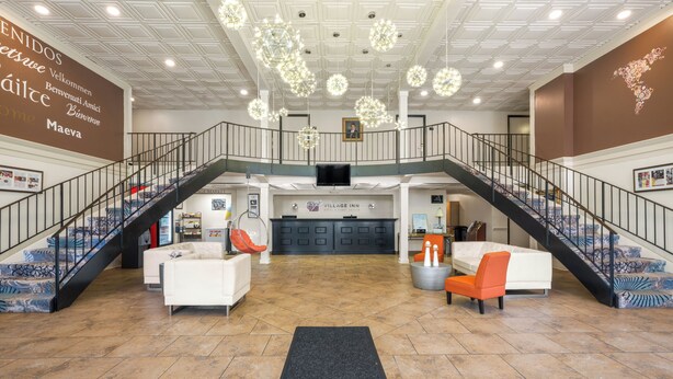 A spacious lobby with a central seating area, a staircase, and a reception desk. - Village Inn Clemmons/Winston Salem, Trademark by Wyndham (Clemmons)