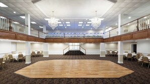 A spacious hall with a wooden floor, white walls, and a balcony with railings. - Village Inn Clemmons/Winston Salem, Trademark by Wyndham (Clemmons)