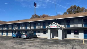 A motel with a sign indicating an office. There are multiple rooms with balconies, and a parking lot with several cars. - Motel 6 Hurricane, WV (Hurricane)