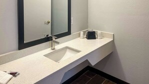 A modern bathroom with a white sink, a large mirror, and a towel on the counter. - Motel 6 Hurricane, WV (Hurricane)
