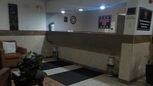 A reception area with a check-in counter, a clock, and a sign for the American Inn.