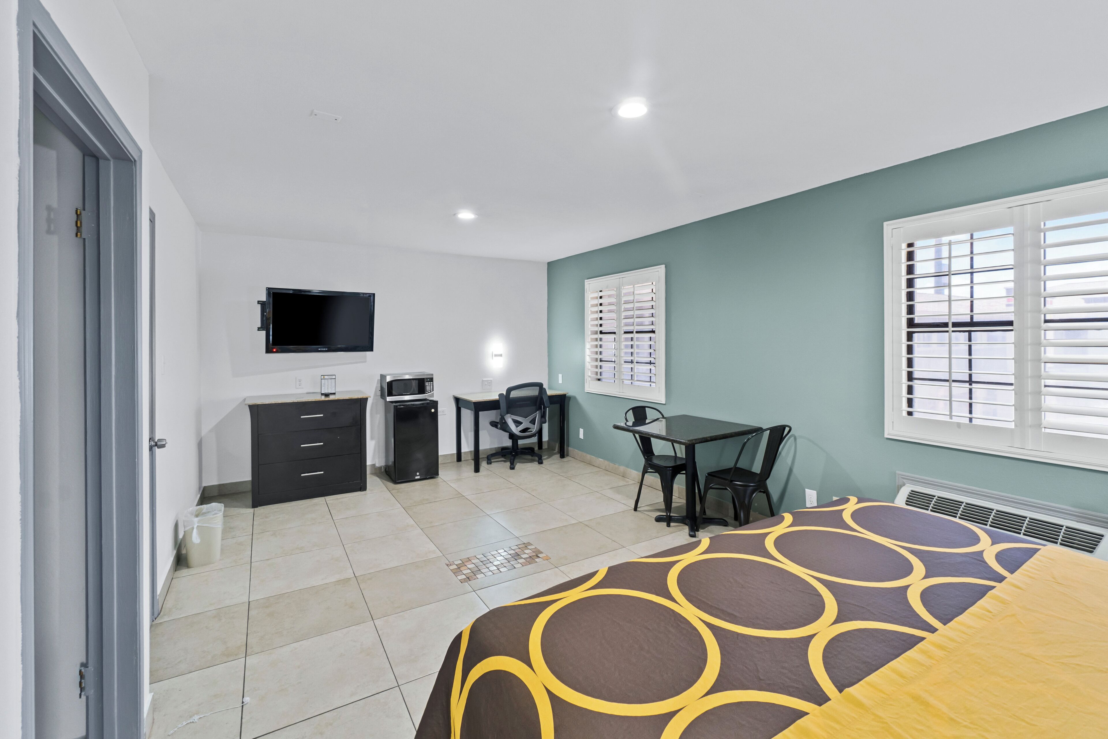 Un dormitorio con cama, escritorio, silla, televisión y ventana.