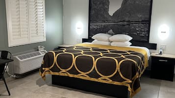 A bedroom with a bed, a window with blinds, a heater, a nightstand, and a wall-mounted light.