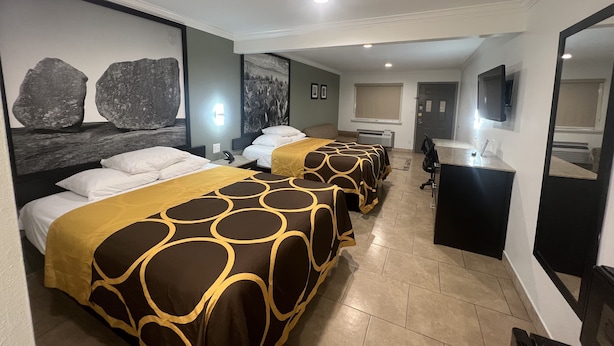 Habitación de hotel con dos camas, un escritorio, un espejo y baño.