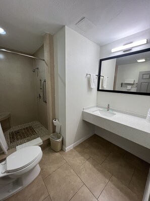 A bathroom with a shower, toilet, sink, and a large mirror. - Super 8 Wyndham McAllen Downtown- City Center-Plaza Mall-Airport (McAllen)