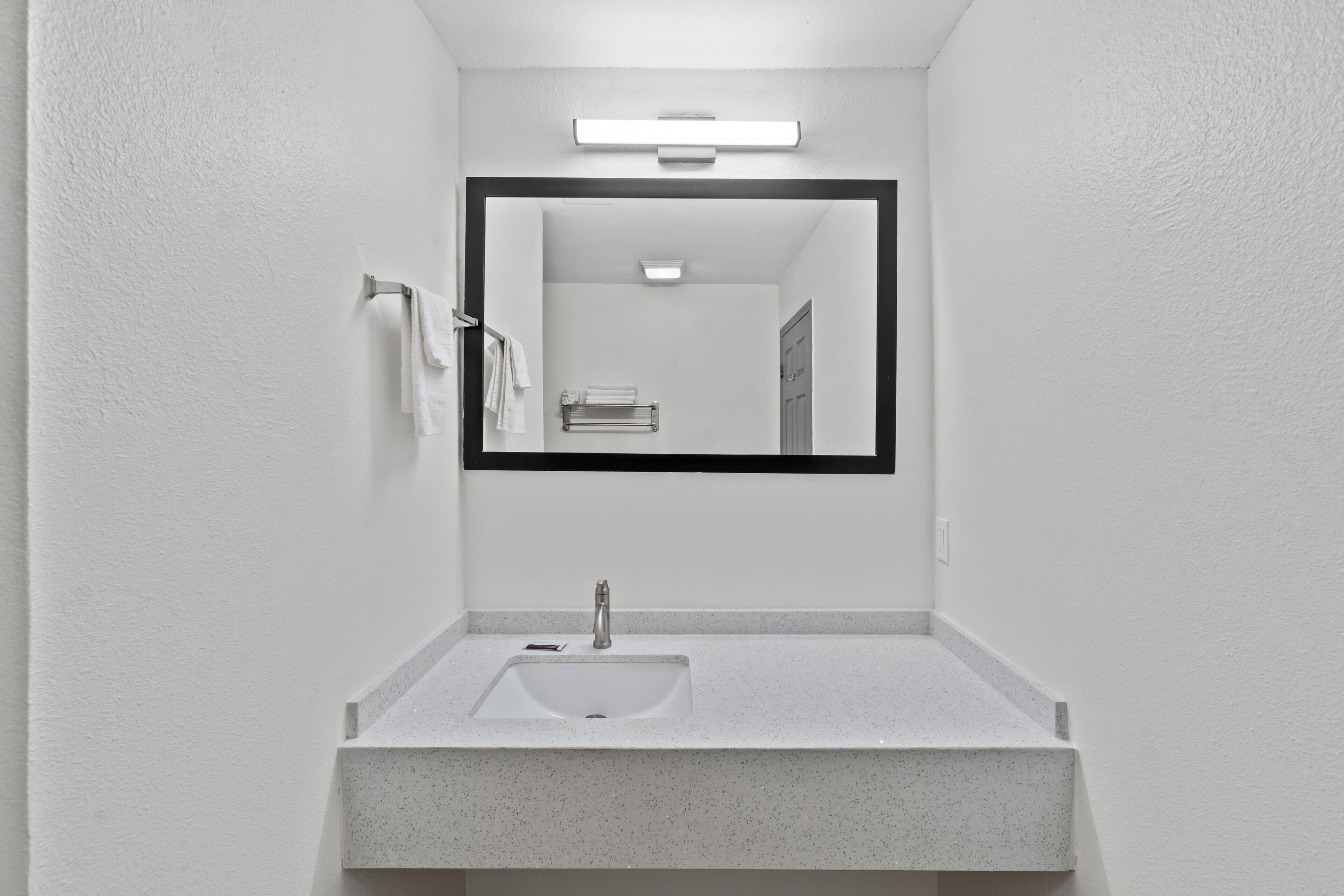 A bathroom with a white sink, a mirror, and a towel rack.