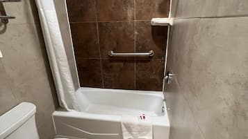 A bathroom with a bathtub, toilet, and shower area.