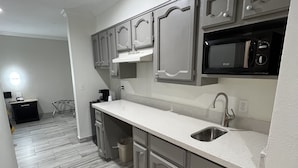 Una cocina moderna con gabinetes grises, un lavamanos de acero inoxidable y un microondas negro.