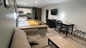 Una habitación de hotel moderna con sofá, cama, escritorio, silla y televisión.