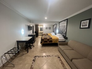 A hotel room with a bed, a desk, a chair, a sofa, and a bathroom visible in the background. - Super 8 Wyndham McAllen Downtown- City Center-Plaza Mall-Airport (McAllen)