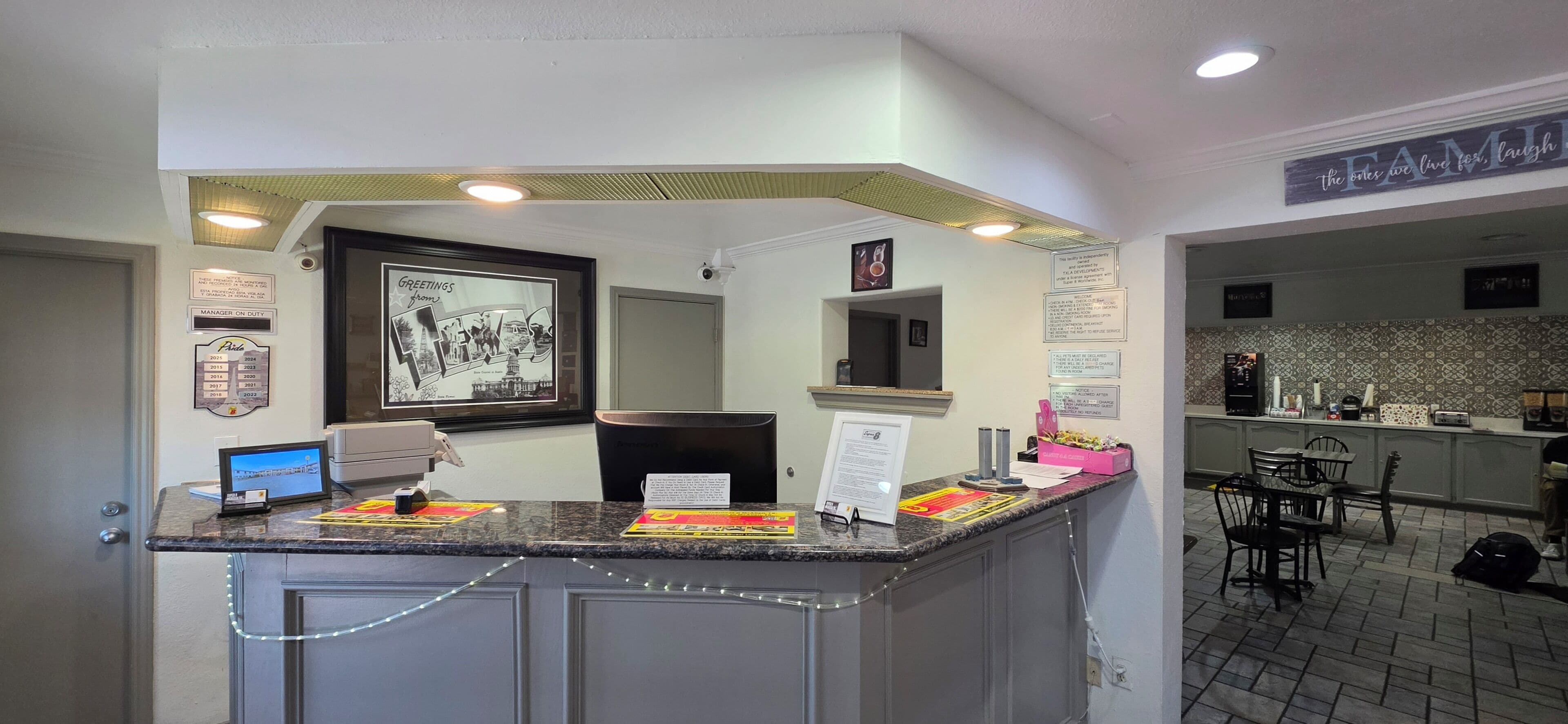 A reception area with a counter, a framed photo, a computer, and a security camera.
