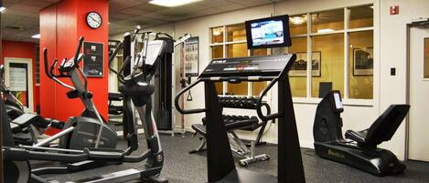 Un gimnasio con cintas de correr, elípticas y equipo de pesas.