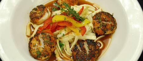 A plate of food with seared scallops, noodles, and sliced bell peppers.